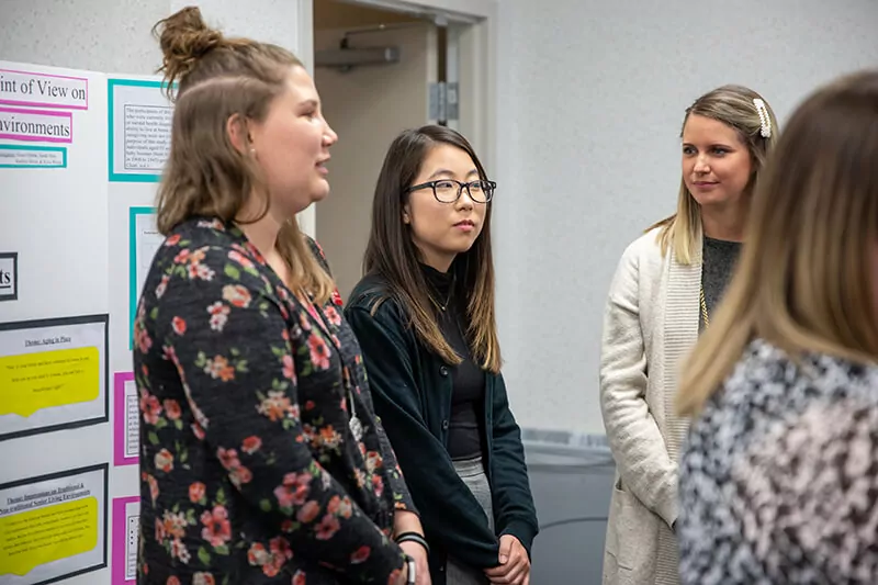 Several students stand beside a display presentation