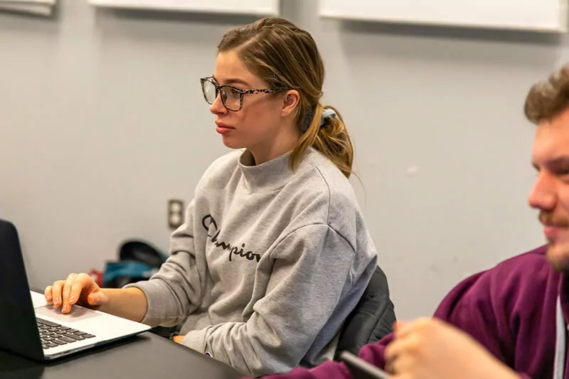 A student listens in class next to her open laptop.