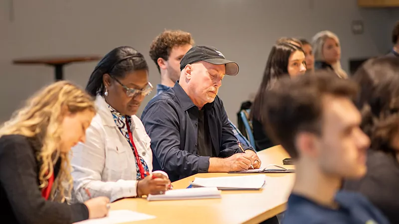 Adult students take notes while listening in class.