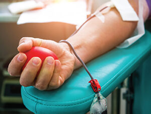 A hand squeezes a blood pressure stress ball that looks like a heart.