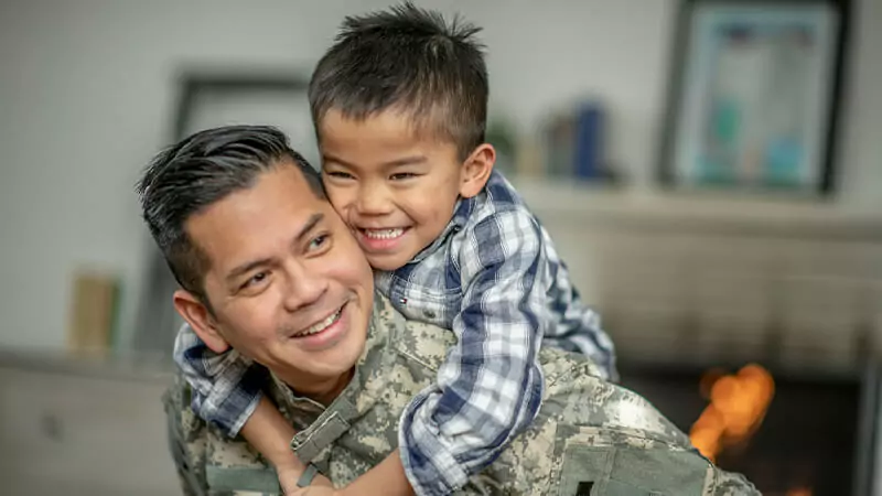 Military service dad smiles while hugging his son.