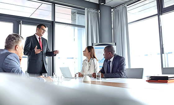 A group of business people discuss at a conference table.