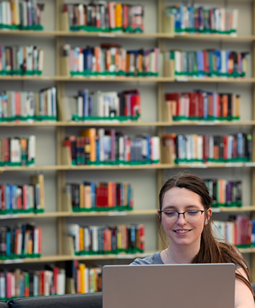 Female student studying on a cpmoyter in a library