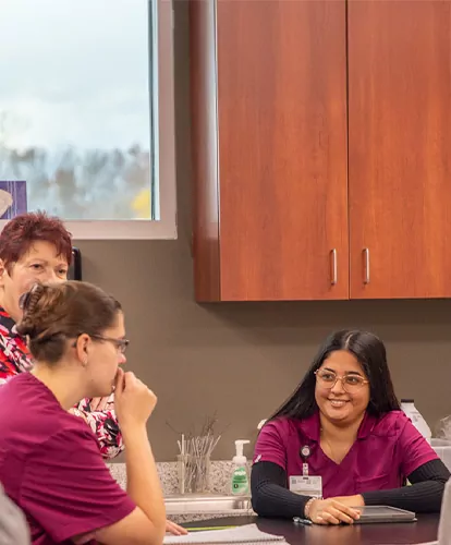 Happy Vet Tech students in scrubs chat in a lab class.