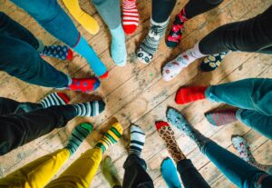 Part of the #LotsOfSocks campaign, this image looks down at a circle of people wearing brightly colored mismatched socks