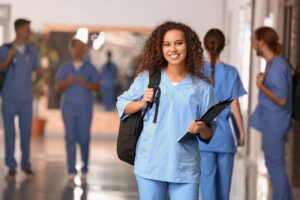 African-American student wearing scrubs in corridor of nursing school.