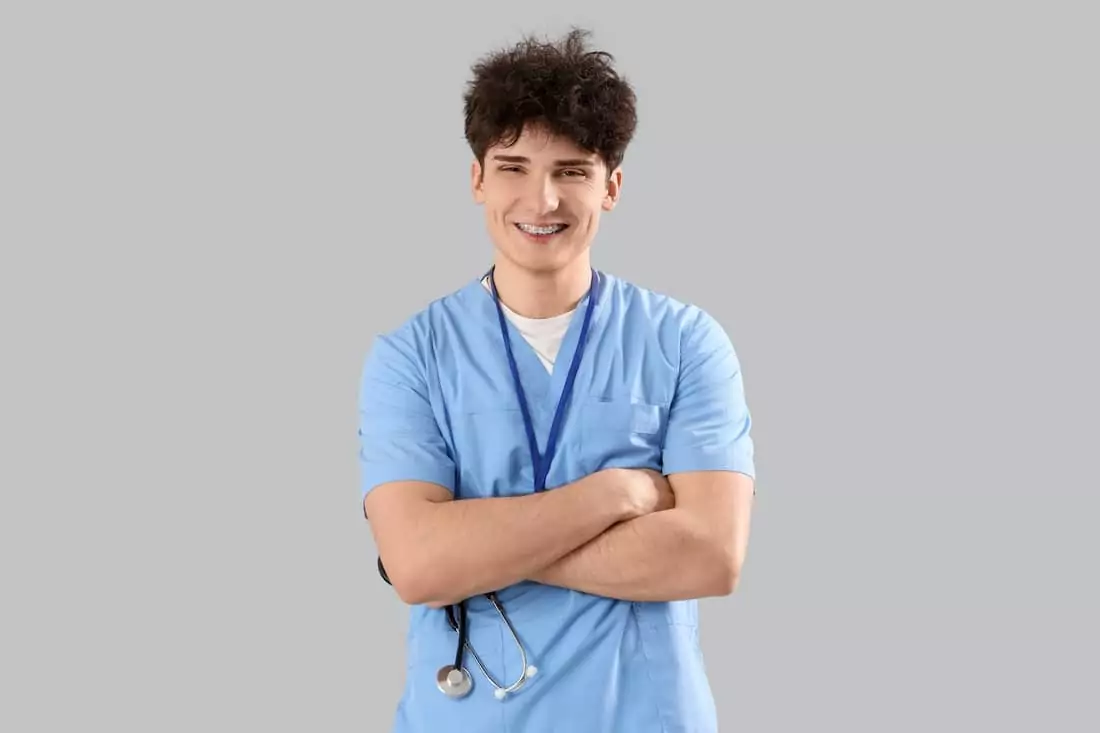 Male nursing intern with stethoscope on light background.