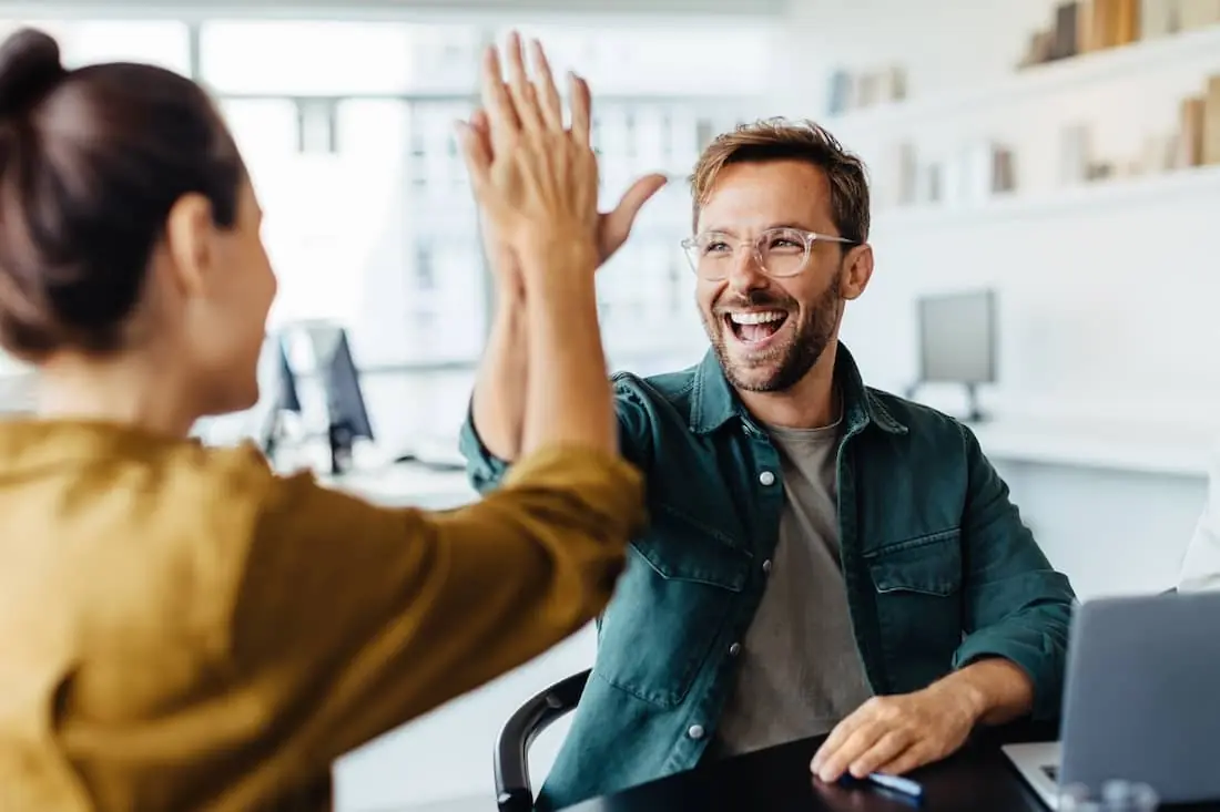 Successful business people giving each other a high five in a meeting.