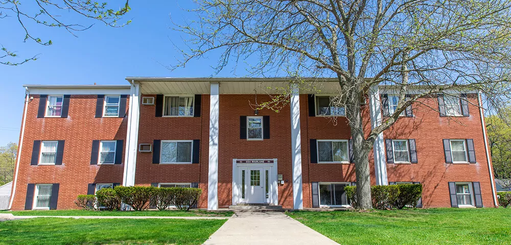 Baker Village apartments exterior (red brick building with white columns) against the blue sky.