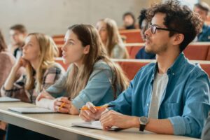 College Students Listening to a Lecturer and Writing in Notebooks.