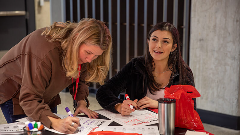 A student and advisor work together on paperwork at a table.