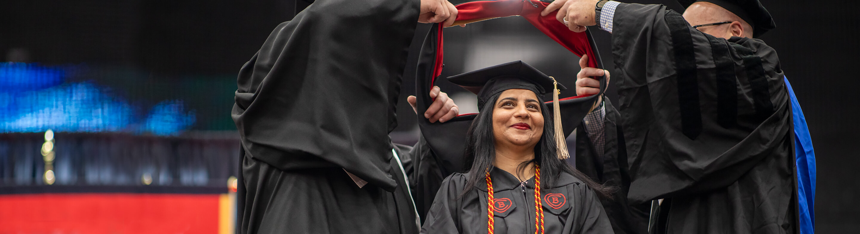 A student smiles while receiving their sash and diploma during the Commencement Ceremony.