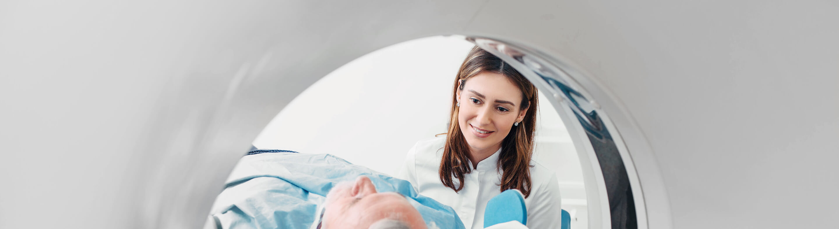 A computed tomography technologist prepares a patient for a scan.