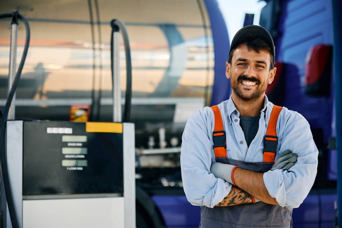 Portrait of happy truck mechanic with arms crossed looking at camera.