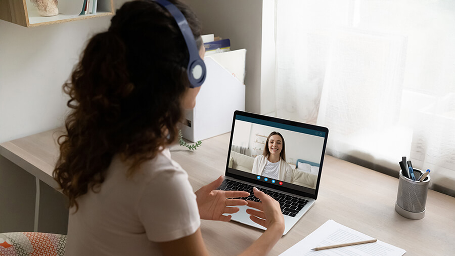 A young woman speaks with a therapist during a video call.