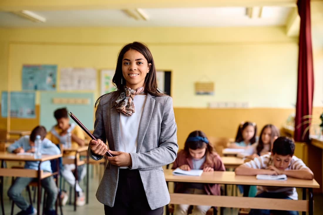 Happy Hispanic teacher during a class at elementary school looking at camera.