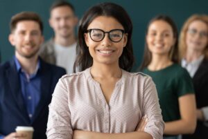 Happy multiracial female business leader standing in front of team smiling at camera. 