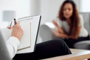 Psychologist writing in notebook with patient in consultation.
