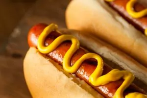 A close up of a hot dog on a bun with mustard.