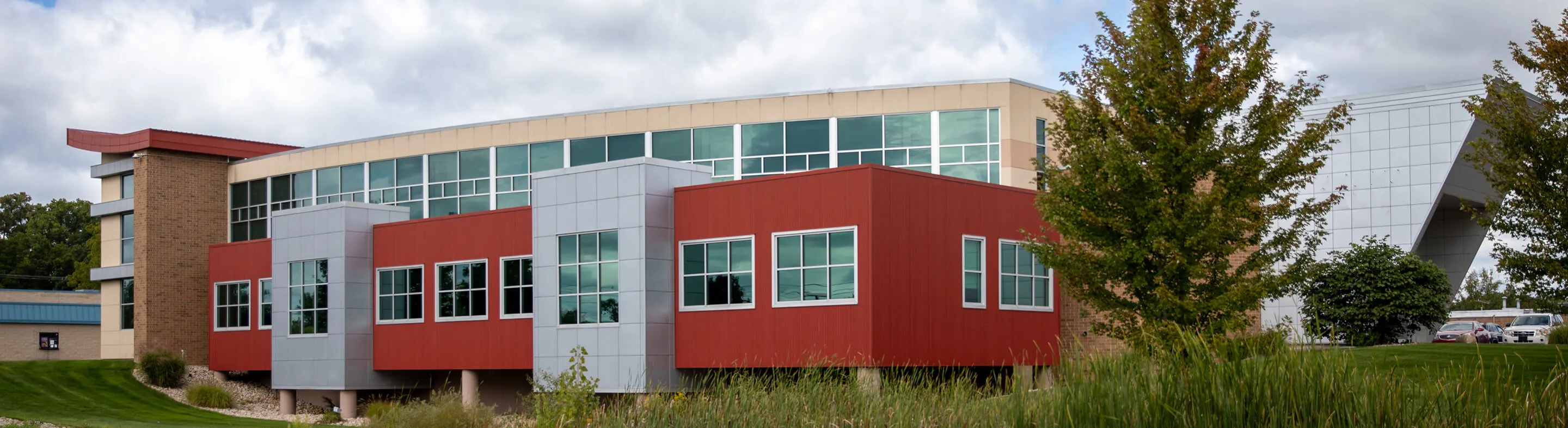 A wide photo of the Jackson campus, featuring a red and silver building with lots of windows.