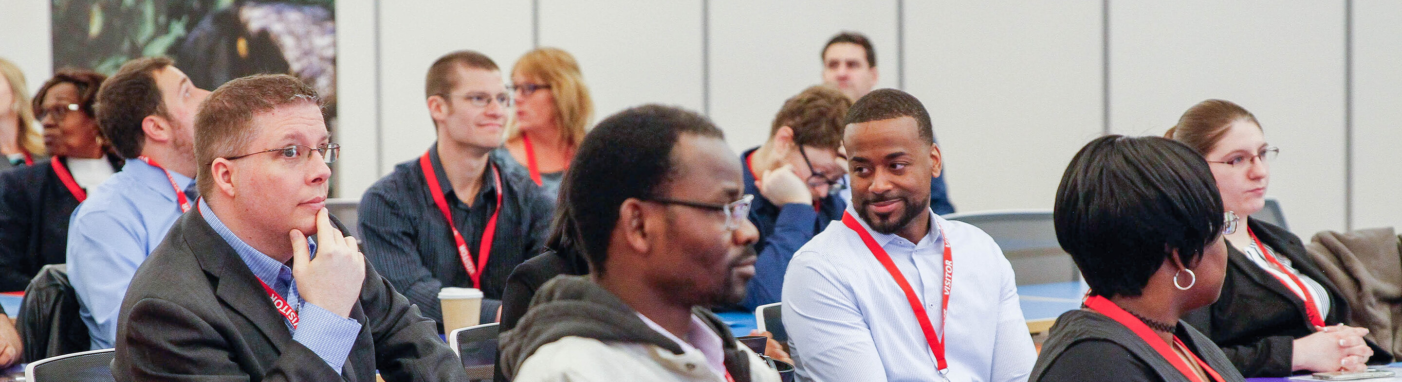 Students in professional clothing sit in a lecture hall wearing red Baker College lanyards.