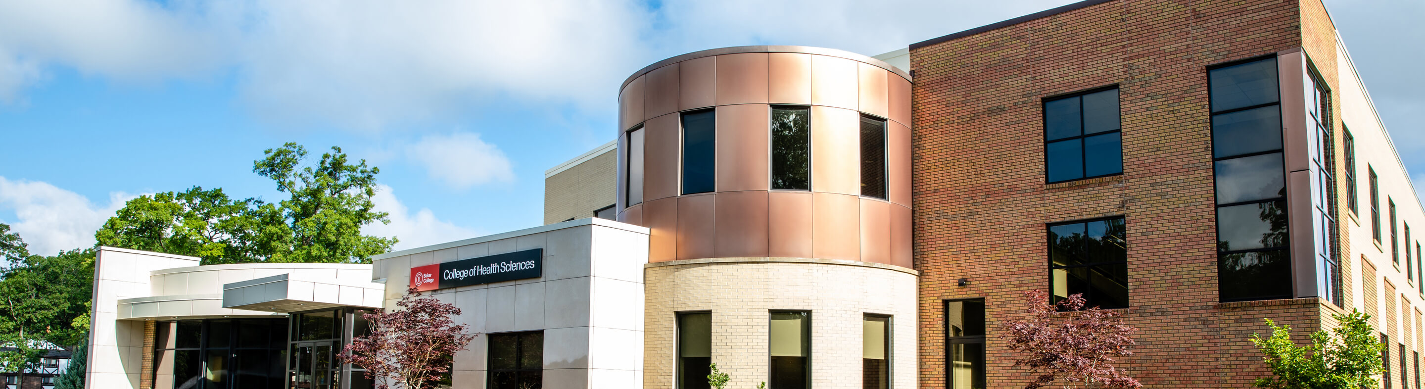 An exterior photo of the Muskegon campus, including the College of Health Sciences sign, from the right side. The image is angled toward the left.