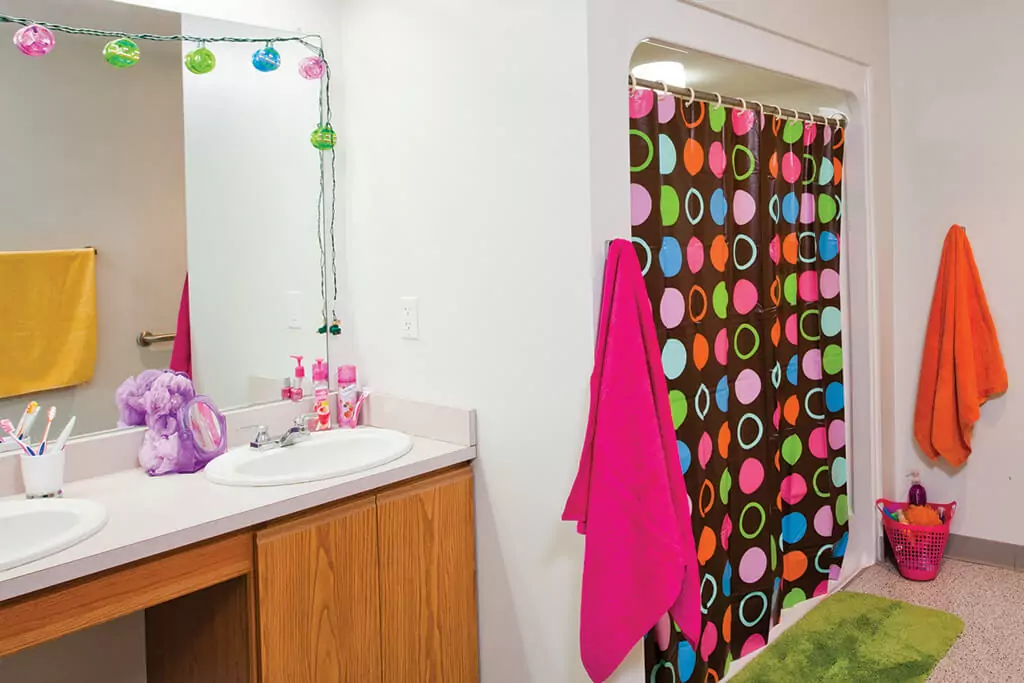 Bathroom with double vanity sink and colorful shower curtain.