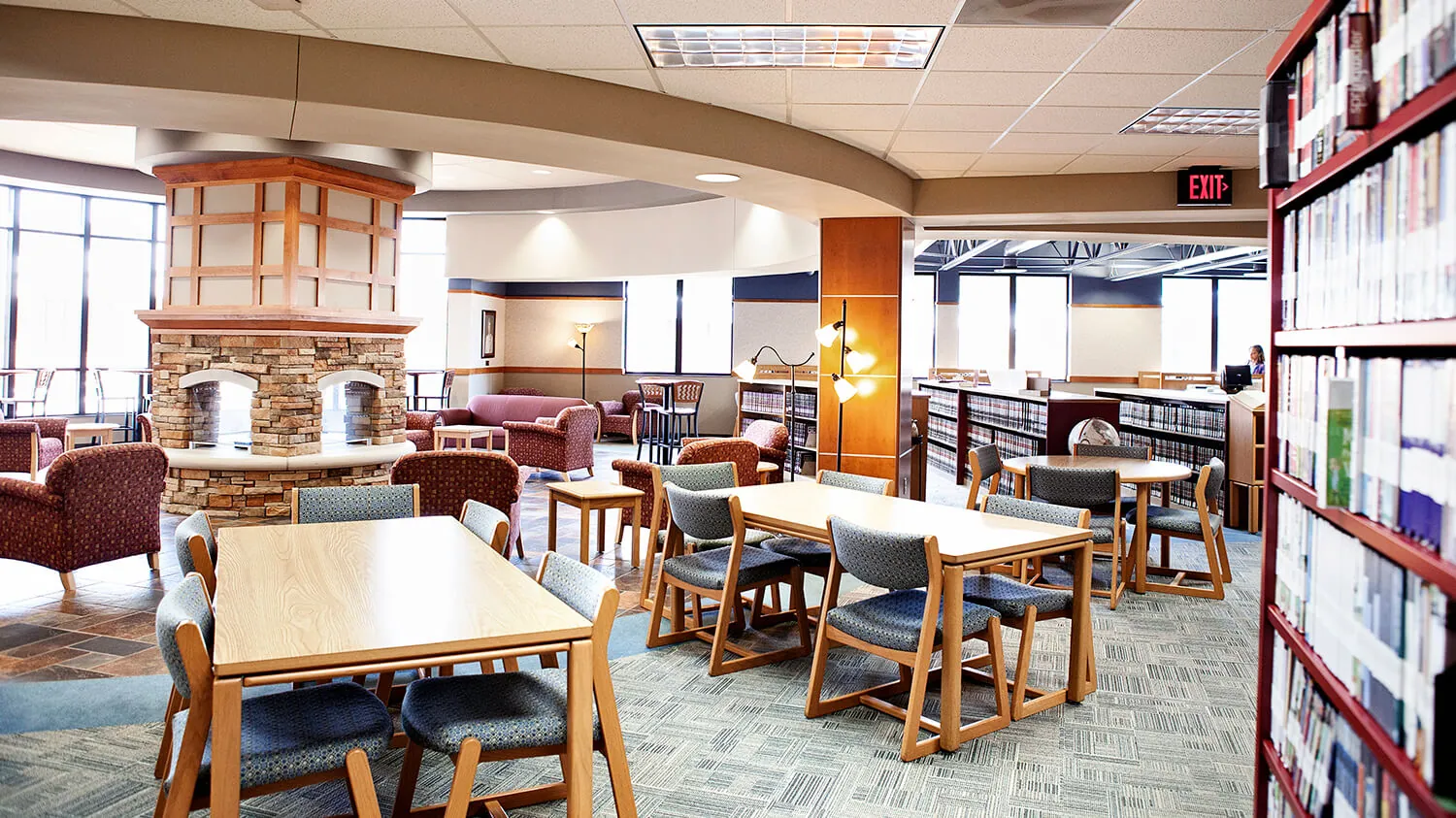 The Academic Resource Center in the Muskegon campus, showing lots of study tables with chairs around a fireplace.