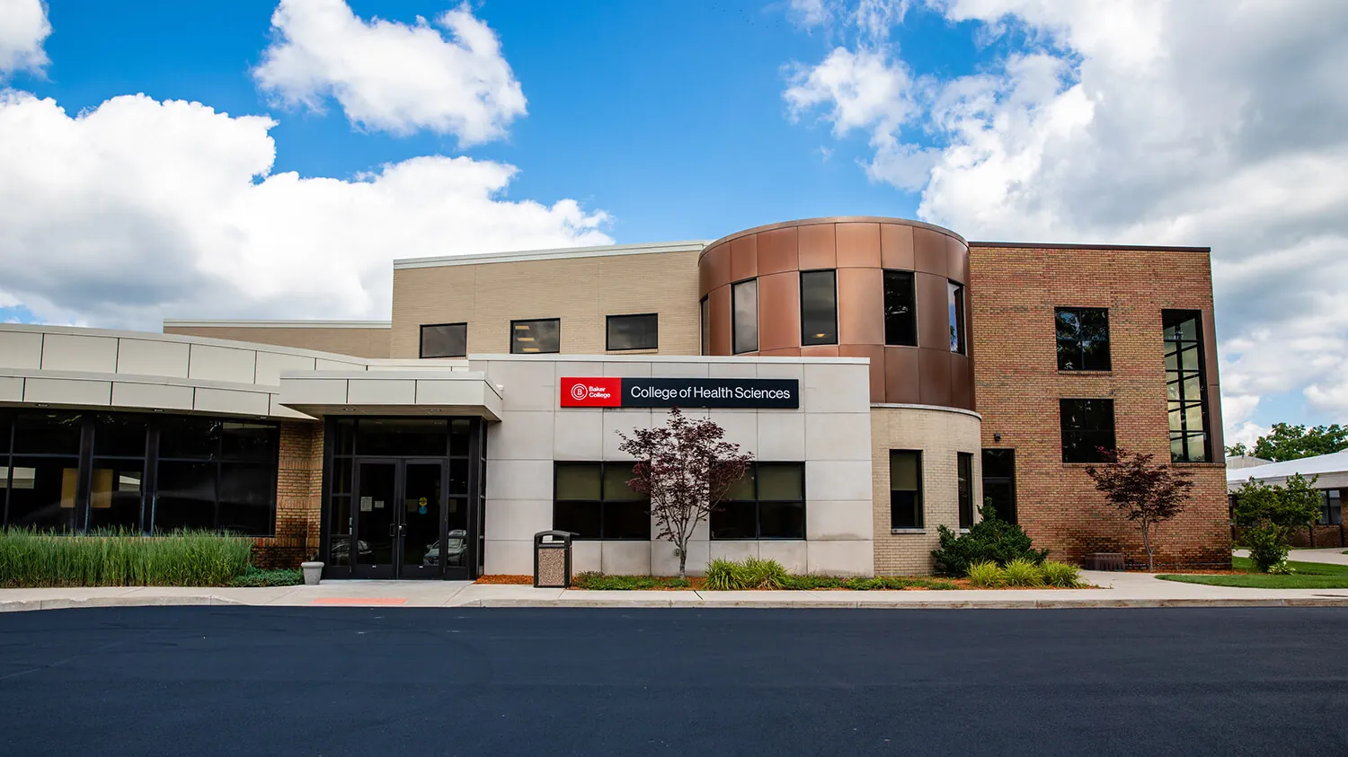 An exterior photo of the Muskegon campus, centered on the College of Health Sciences sign.