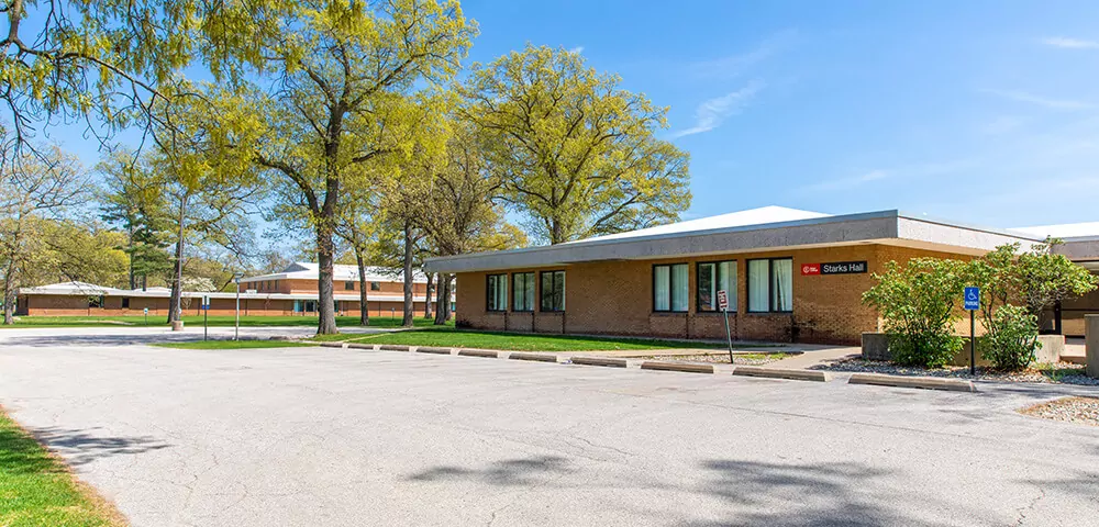 Starks Hall exterior, a red brick building and parking lot against a blue sky