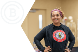 A student wearing a Baker College Bees T-shirt proudly smiles.