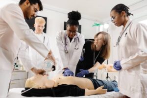 Nursing students learn CPR and first aid techniques during a training session using a CPR dummy.