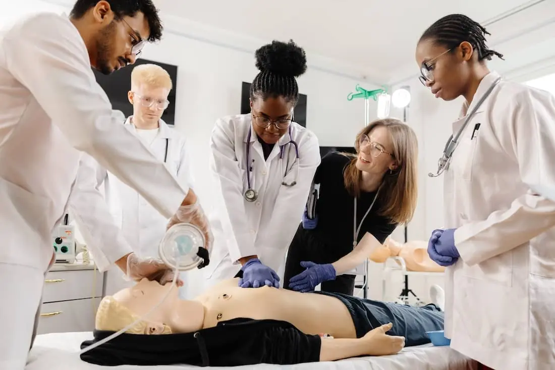 Nursing students learn CPR and first aid techniques during a training session using a CPR dummy.