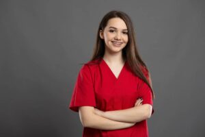 Portrait of a young and smiling nurse wearing red scrubs.