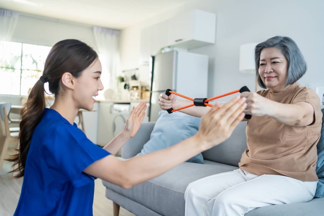 Asian mature older woman doing physiotherapist with support from a therapist.