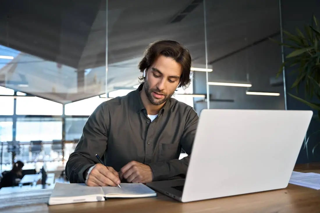 Busy professional young business man wearing earbuds working in office.
