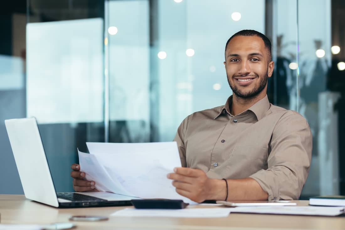 Portrait of young successful hispanic businessman inside office, man smiling and looking at camera