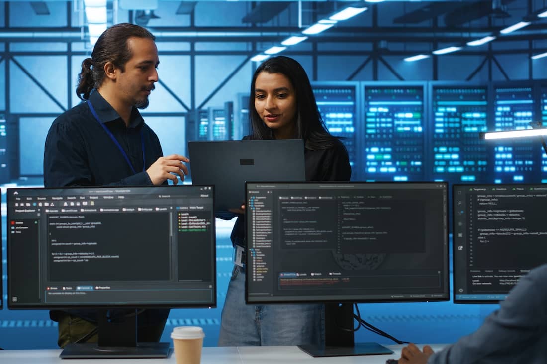 Programmer and supervisor in server room looking for equipment misconfigurations, doing brainstorming. 