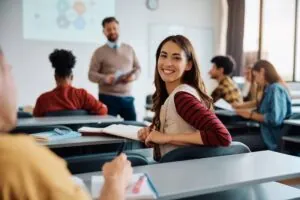 Happy college student during a lecture in the classroom looking at camera.