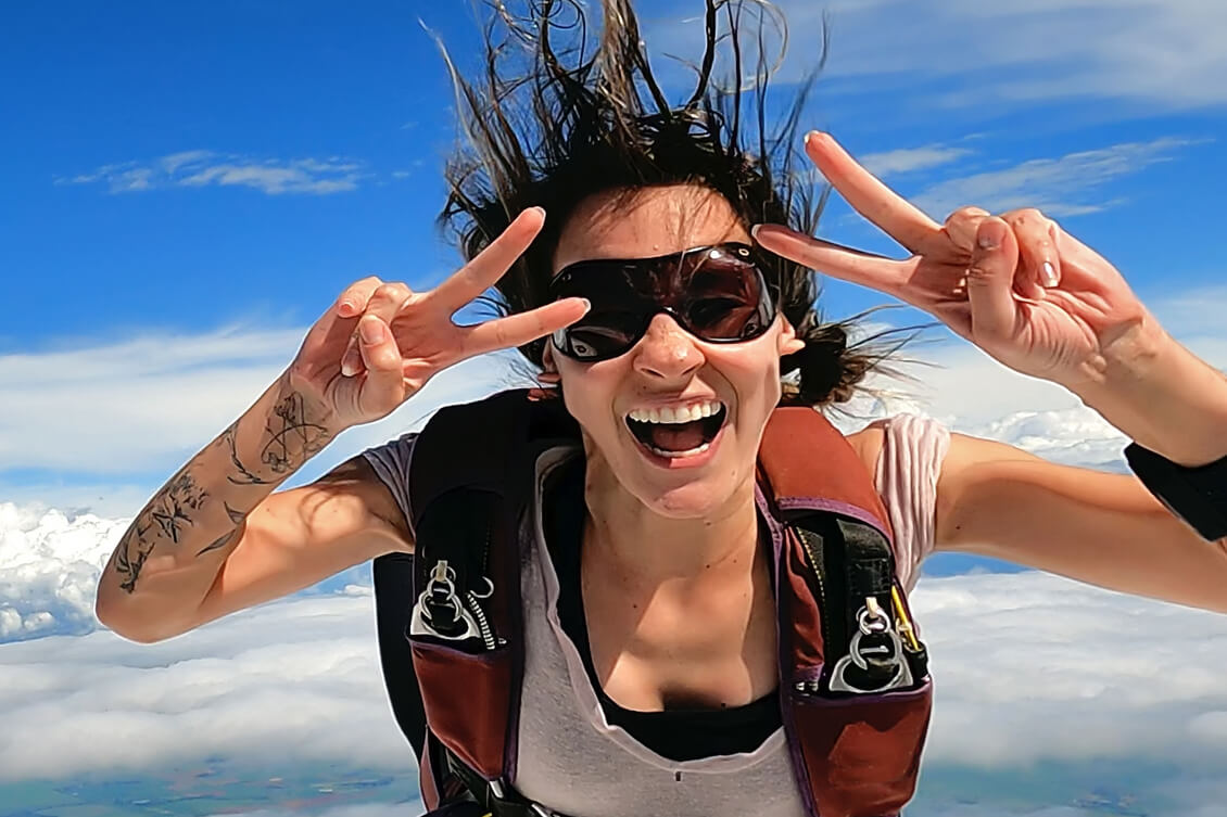 A woman smiling at the camera while skydiving