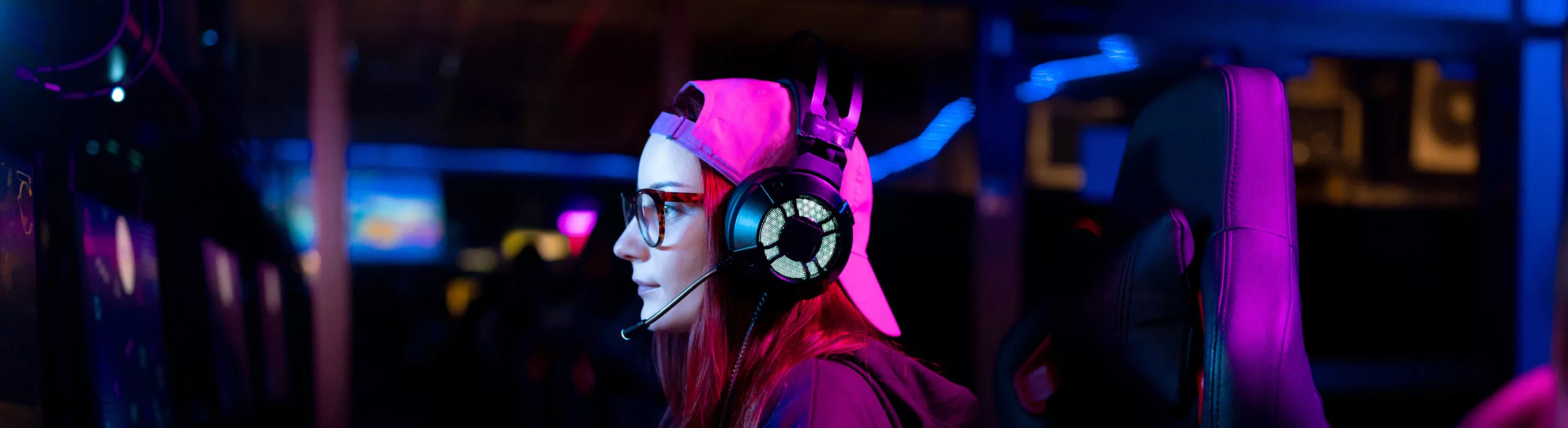 A student plays Esports on a computer while wearing a headset with a microphone and noise-canceling headphones.