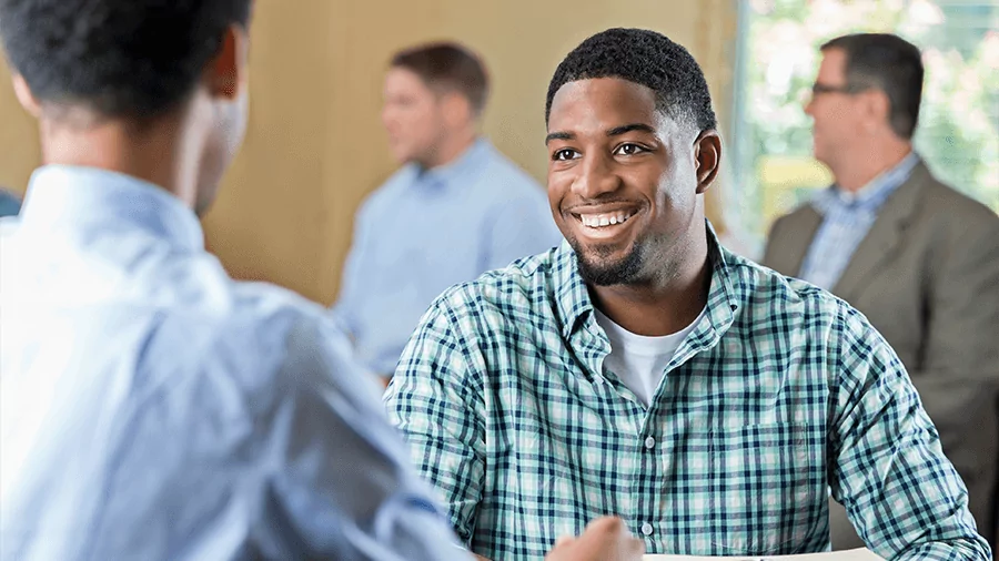 A student smiles while sitting at a table with an advisor.