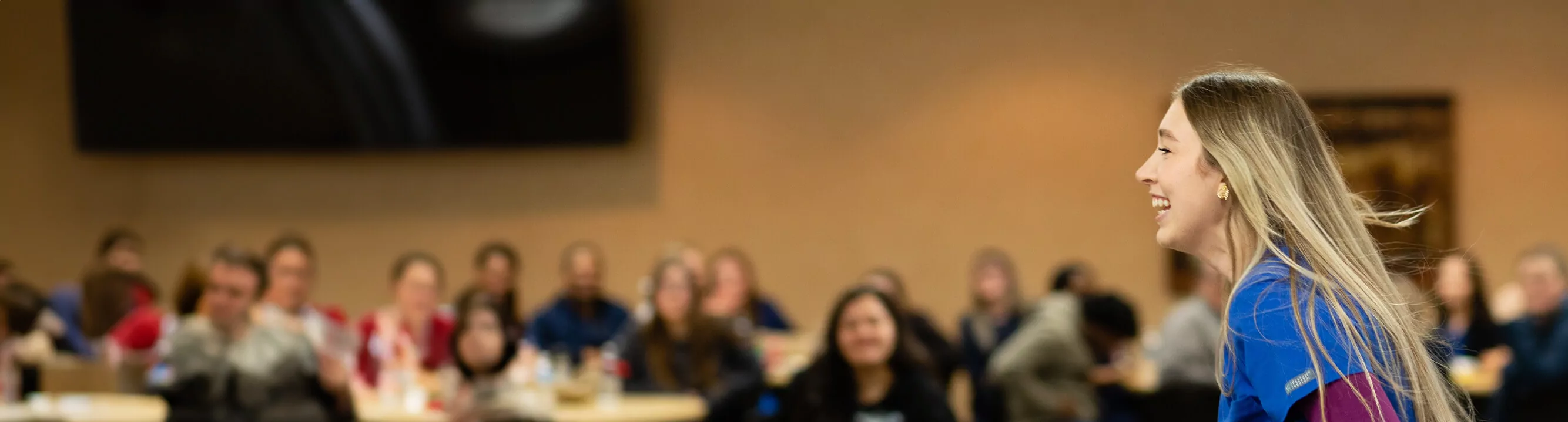 A student smiles as she stands in front of her class. 