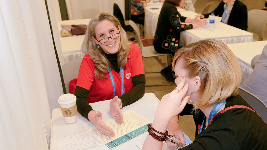 A staff member in a red Baker shirt assists a student.