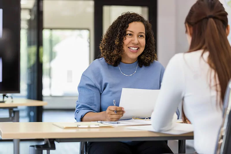 Two people sit at a table with paperwork.