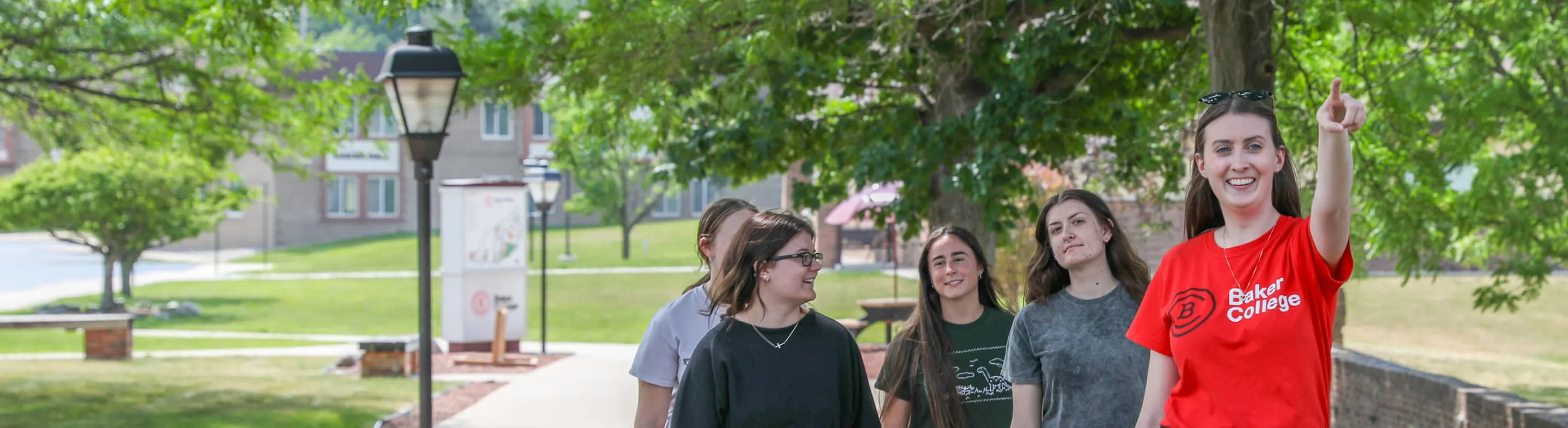 A campus counselor leads a tour for prospective students, pointing out a landmark that sits outside of the frame.