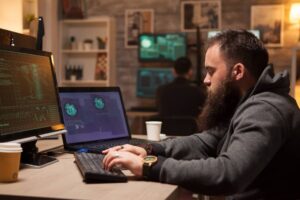 Adult student hacker typing a virus on computer to break firewall security.