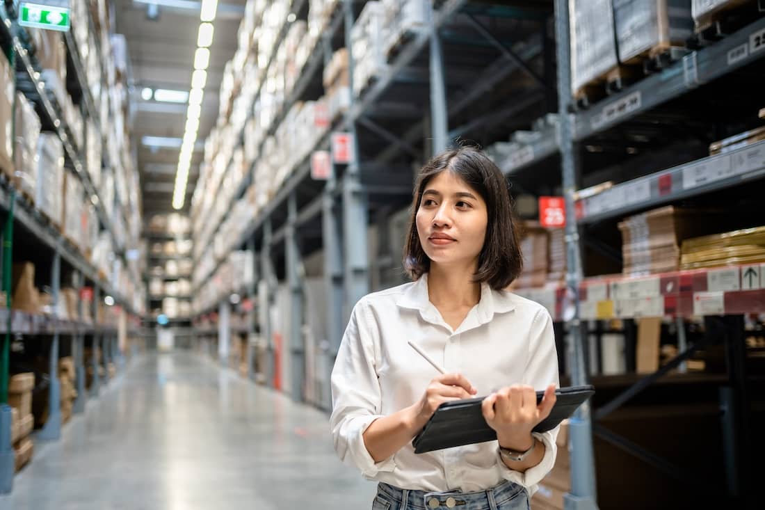 Woman worker using a smart warehouse management system, checking the stock inventory.
